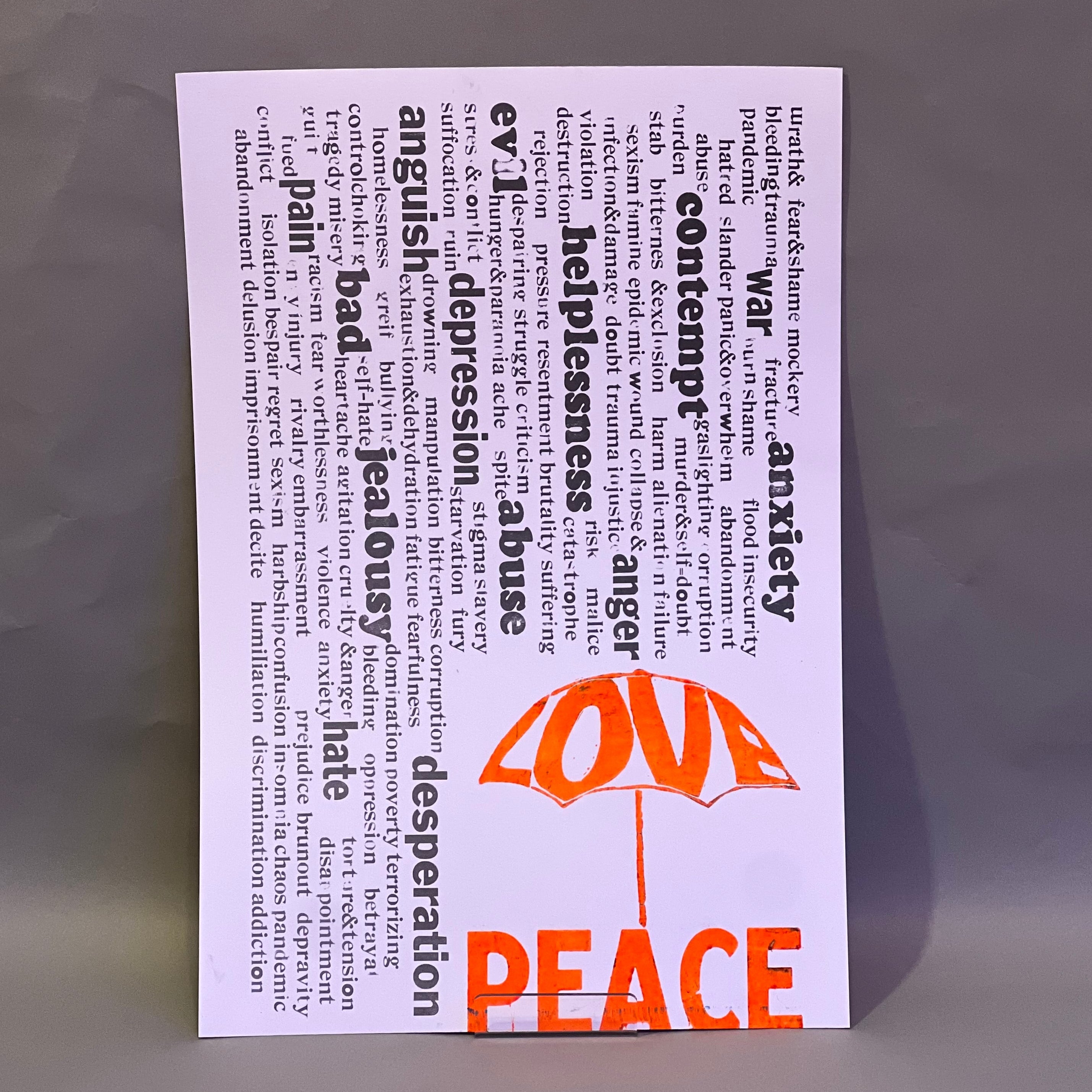 Rain of unpleasant words falling from above, while the word “Love” forms an umbrella that offers protection. Beneath it, the word “Peace”