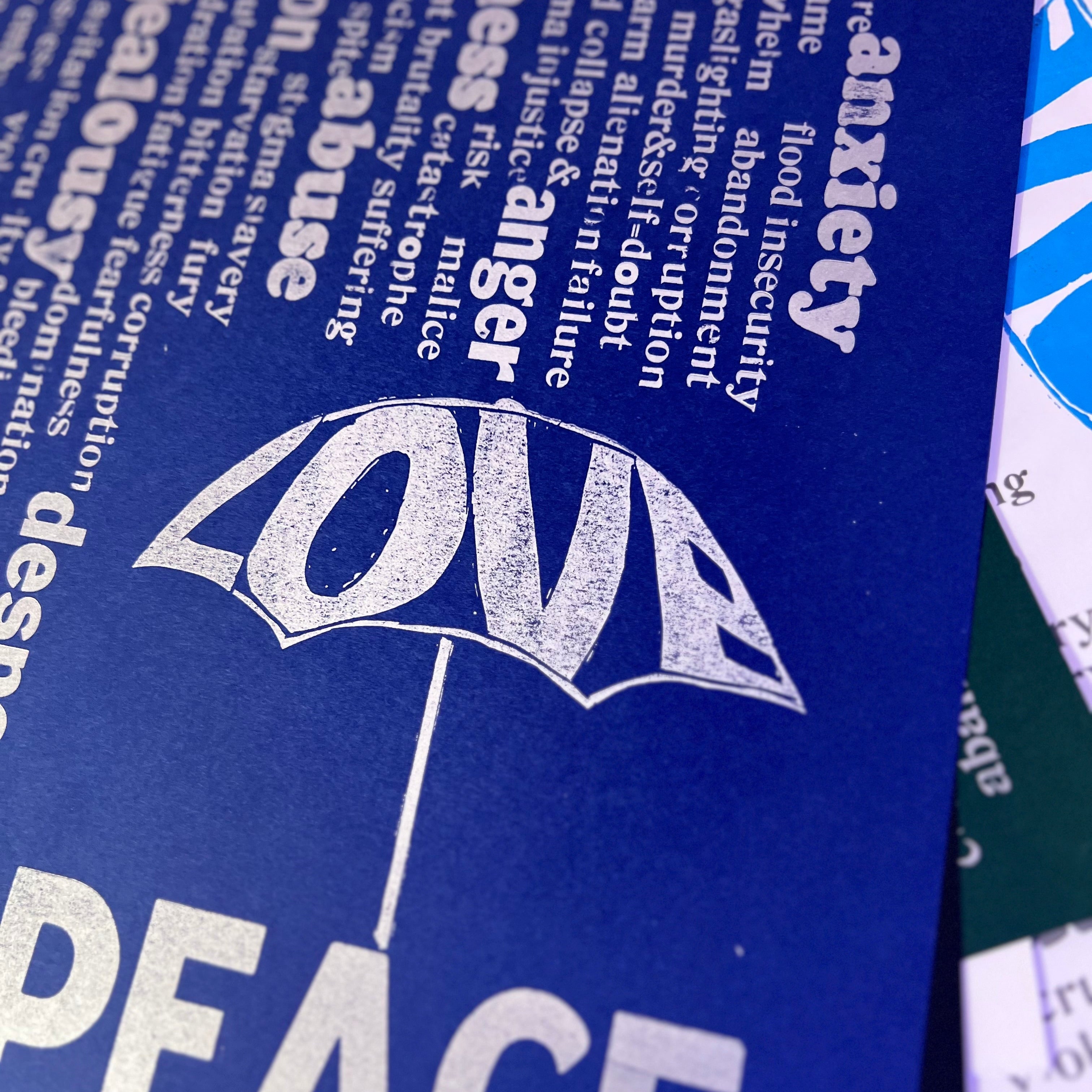 Rain of unpleasant words falling from above, while the word “Love” forms an umbrella that offers protection. Beneath it, the word “Peace”
